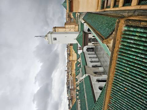       Rooftop view over the green-tiled courtyard and minaret of a historic Fes mosque.
  