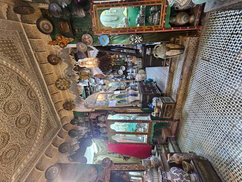       Colorful antique shop interior with patterned mosaic floors, pottery and ornate lanterns.
  