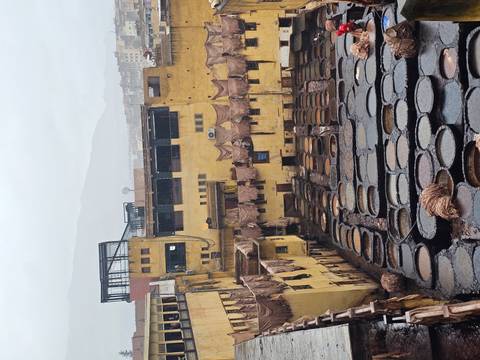      Close view of circular dye pits at a leather tannery with dripping hides overhead.
  