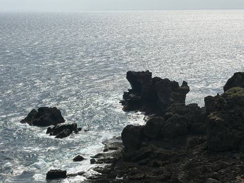       Sun-speckled ocean crashes against jagged volcanic rocks at Taiwan's southern coast.
  