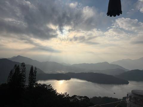       Soft morning light breaks through clouds over misty mountains and Sun Moon Lake.
  
