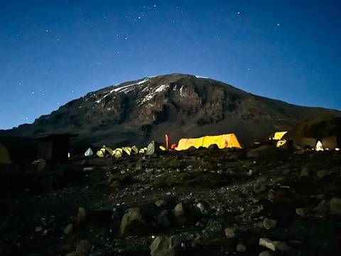       Night view of illuminated tents under a starry sky at the base of Mount Kilimanjaro
  
