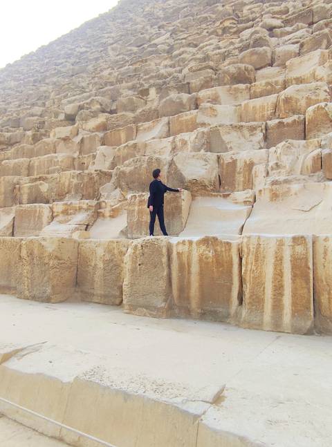       Solo traveler standing on the massive stone blocks of the Great Pyramid of Giza.
  