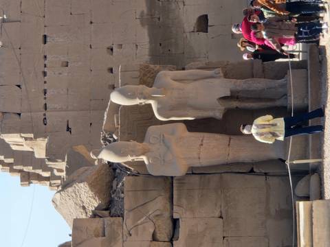       Traveler observing colossal twin statues standing among the ruins of Luxor Temple.
  