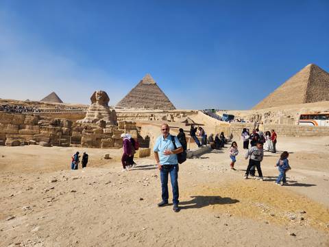       Crowds of visitors gather near the Sphinx with the three Great Pyramids rising behind.
  