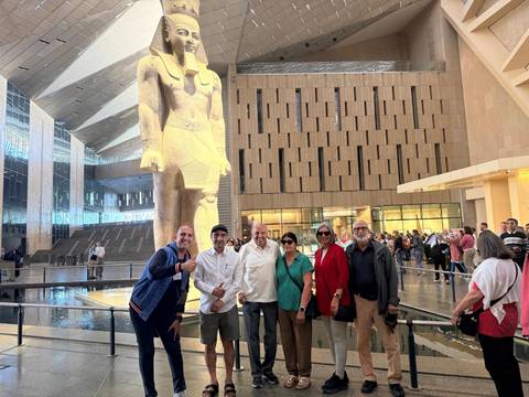       Visitors gather for a photo beneath the colossal statue in Cairo’s Grand Egyptian Museum atrium.
  