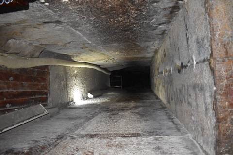       Dimly lit narrow tunnel descending inside an ancient pyramid.
  
