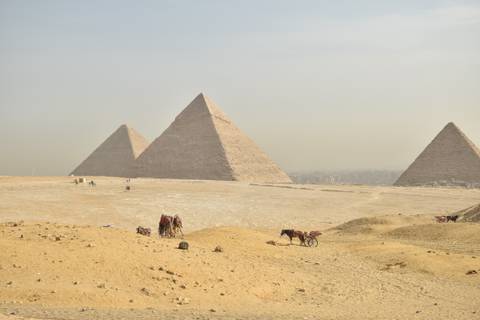       Panoramic view of the three Great Pyramids of Giza fading into desert haze.
  