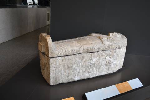       Ancient Egyptian stone sarcophagus displayed on a museum plinth.
  