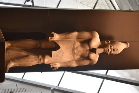       Stone statue of an ancient pharaoh exhibited indoors under soft lighting.
  