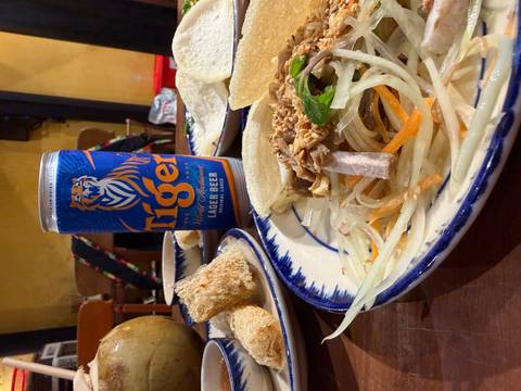       Vietnamese meal with Tiger lager, salad, and fried rolls on traditional ceramic plates.
  