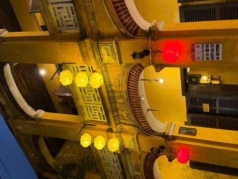       Yellow colonial-era building decorated with glowing lanterns in the evening.
  