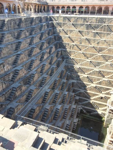       Geometric maze of stone steps at Chand Baori stepwell with dramatic shadows on the walls.
  