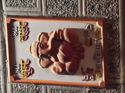       Small wall plaque of the Hindu deity Ganesha rendered in relief under dim lighting.
  