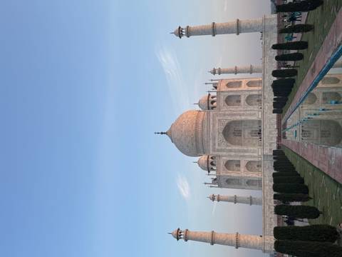       The Taj Mahal stands symmetrically in early evening light with its reflection in the long central pool.
  