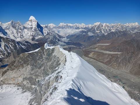       Stunning aerial view of a razor-thin snowy ridge leading to towering Himalayan giants and valleys below.
  