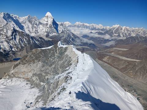       Expansive Himalayan vista of jagged snow ridges contrasted with rocky valleys under crystal clear skies.
  