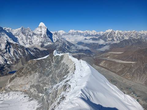       Wide alpine scene showing a knife-edge snowy crest with towering Ama Dablam and surrounding Himalaya.
  
