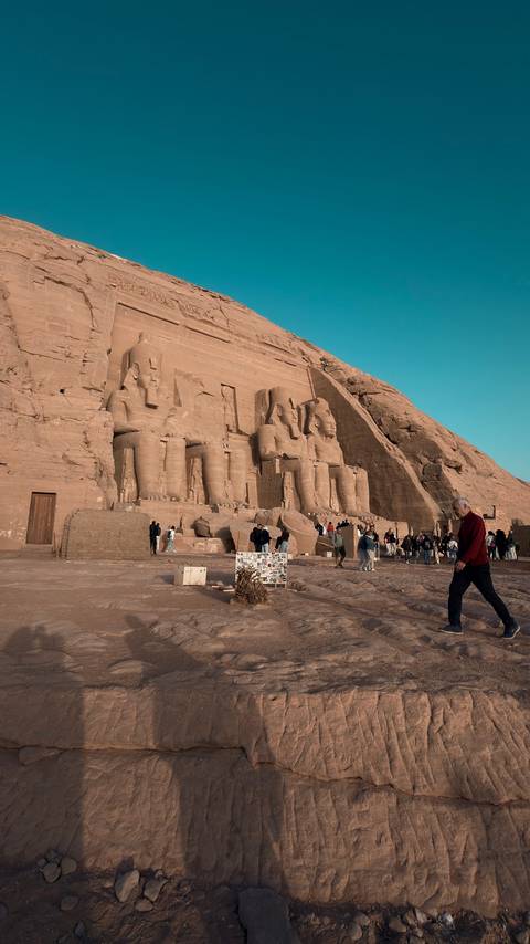       Wide view of Abu Simbel temple façade with crowds of tourists in warm afternoon light
  