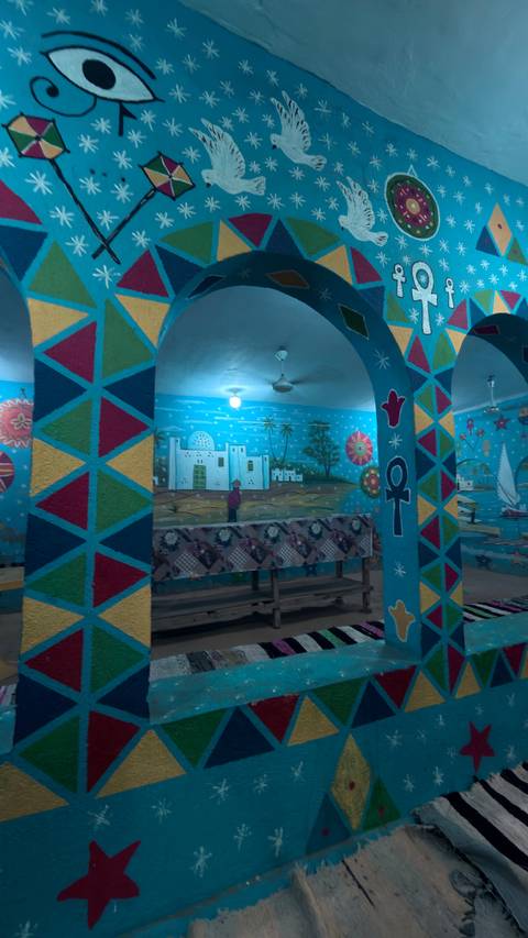       Interior of a Nubian house painted bright blue with colorful symbols and murals
  