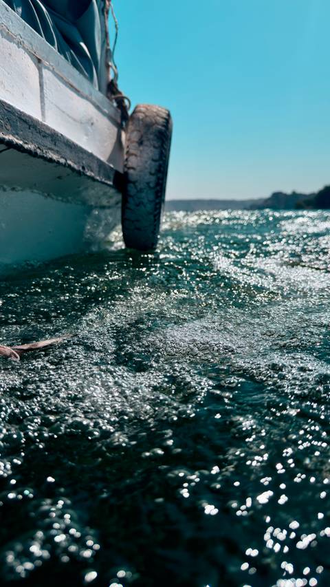       Abstract close-up of sun-sparkled water splashing around a boat tire
  