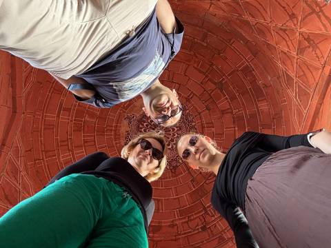       Creative upward shot of three travellers standing beneath an ornate red stone dome
  