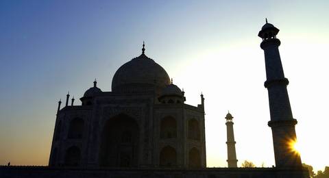       Silhouetted against a rising sun, the Taj Mahal and its minarets create a dramatic sunrise scene.
  