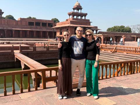       A family poses on a red sandstone terrace above ornamental pools at Fatehpur Sikri palace.
  