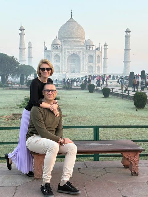       A couple poses playfully on a misty morning with the Taj Mahal blurred in the background.
  