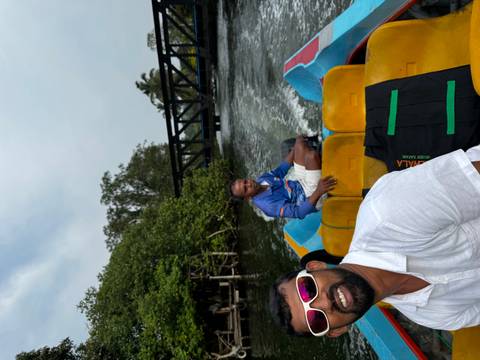       Smiling travellers ride a small motorboat through mangrove-lined waterways with a bridge ahead.
  