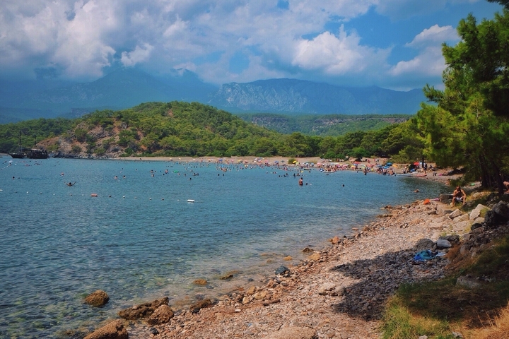 Beach surrounded by lush mountains and turquoise water.