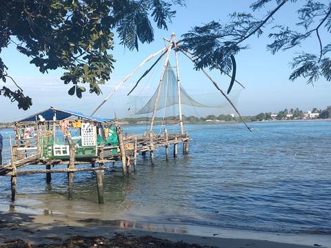       Traditional Chinese fishing net on wooden pier extending into the blue Arabian Sea in Kochi.
  
