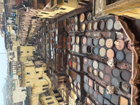       Aerial view of Fes tanneries with workers and rows of colorful stone dye vats.
  