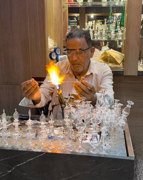       Glass artisan shaping delicate pieces using a torch with bright flame.
  