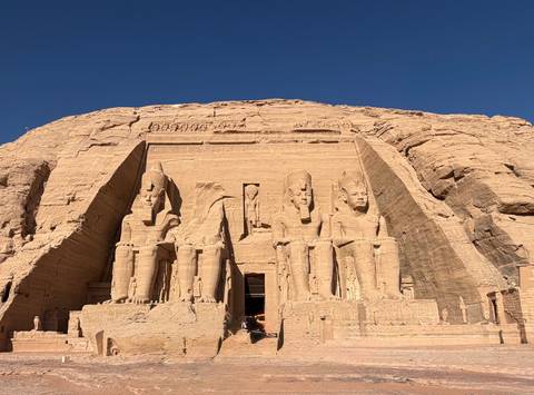       Front view of Abu Simbel’s colossal statues and entrance in bright sunlight.
  