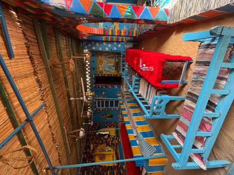       Color-saturated Nubian style café with blue benches and sand floor.
  
