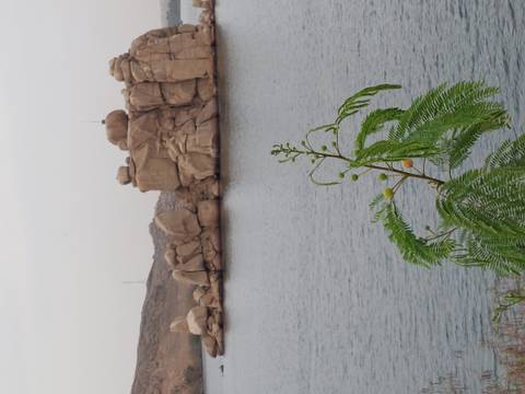       Calm lake bordered by large rounded granite boulders under an overcast sky.
  