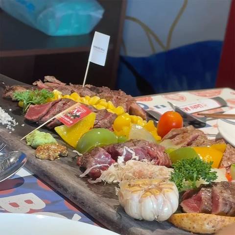       Assorted grilled steak slices with colourful roasted vegetables served on a wooden platter.
  