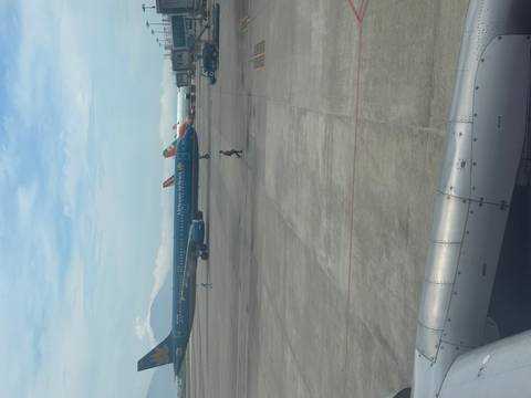       Vietnam Airlines jet parked on an airport apron with other aircraft and distant mountains.
  