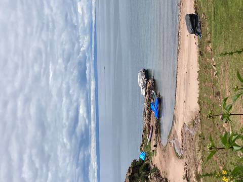       Quiet lakeside cove with sandy beach, small boats and cloudy skies.
  