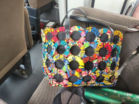       Colorful patterned fabric handbag resting on bus seat.
  