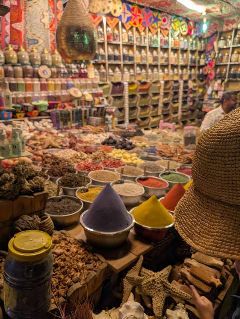       Colorful but slightly soft-focused spice market stall with conical piles of vibrant powders.
  