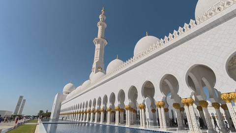       Side perspective of Sheikh Zayed Grand Mosque with reflective pools and gilded columns.
  