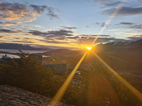       Dramatic sunset over Ushuaia with golden rays streaming across mountains and the Beagle Channel.
  
