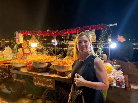      Night market food stall in Thailand with skewers of seafood and festive decorations.
  