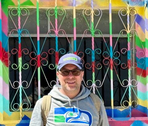       Traveller smiling in front of a multicoloured wrought-iron window in Guatemala
  