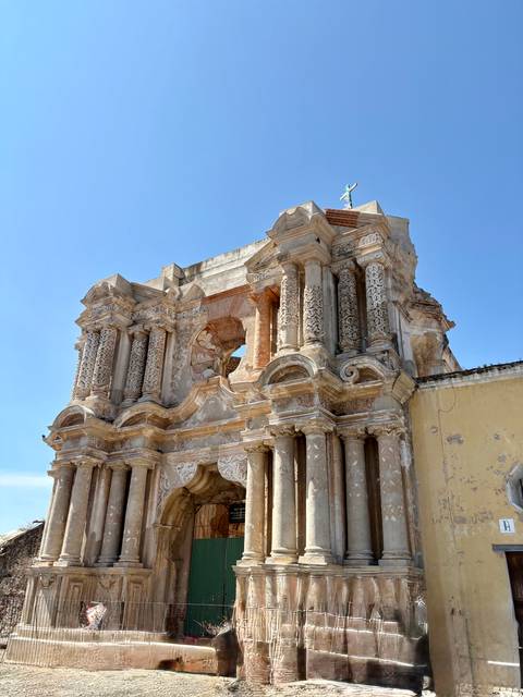       Detailed façade of a crumbling baroque church ruin under a clear sky
  