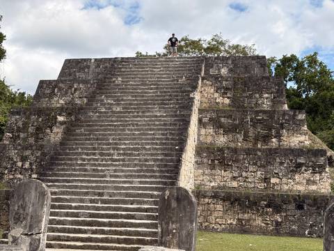       Stepped Mayan pyramid with a single visitor standing triumphantly on the summit
  
