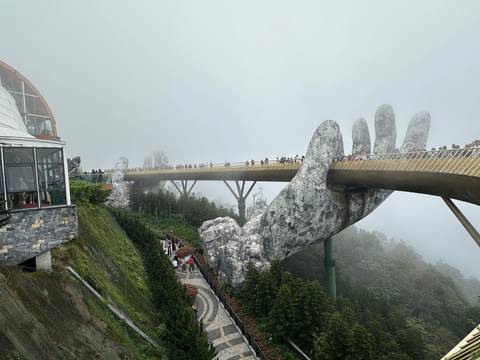       Iconic Golden Bridge at Ba Na Hills supported by giant stone hands shrouded in mist
  