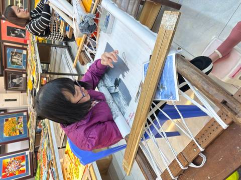       Craftswoman intently weaving detailed silk artwork on a loom inside a workshop
  
